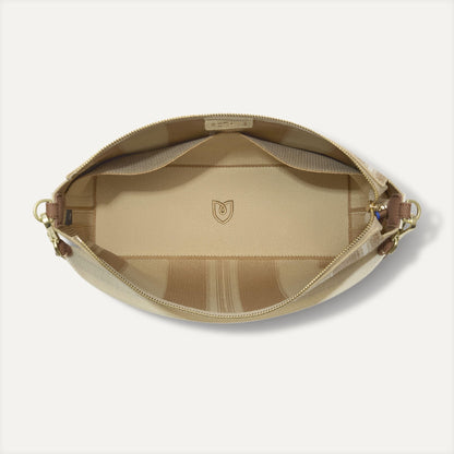 The Daily Crossbody in Oat Latte, shown from the top down, with zipper open and interior exposed.
